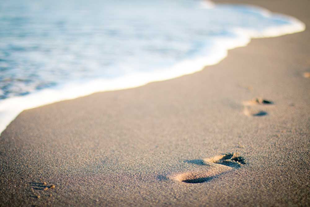 Freedom and Fulfillment - Footprints in sandy beach